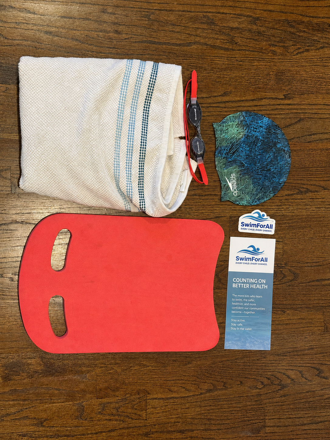 Swim kit contents including towel, kickboard, goggles, swim cap, stickers, and guide
